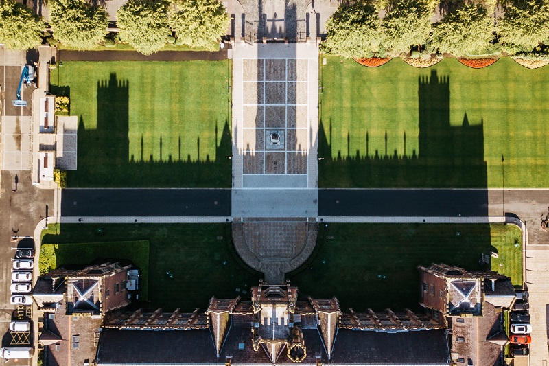 aerial image of Lanyon Building at Queen's University Belfast with shadow cast over grassy quadrangle behind it