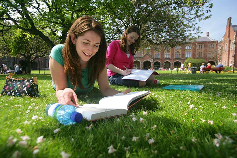 two female students studying on the grass in the Quad