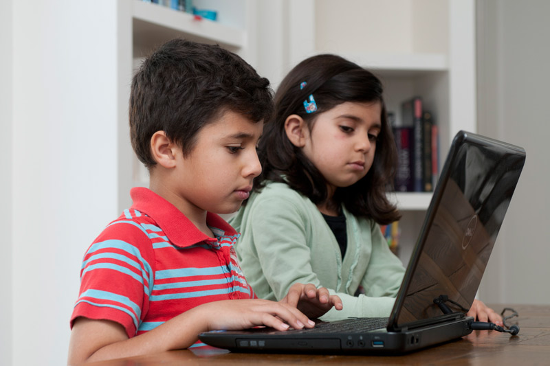 two children using laptops