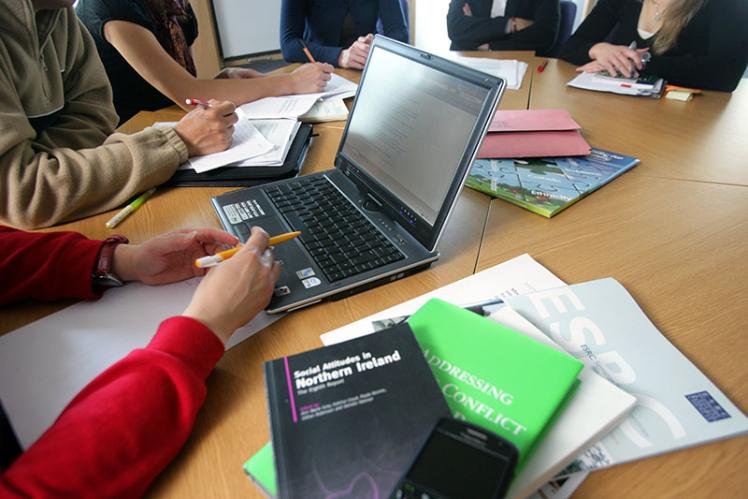 researchers round a table with close ups of research publications in education