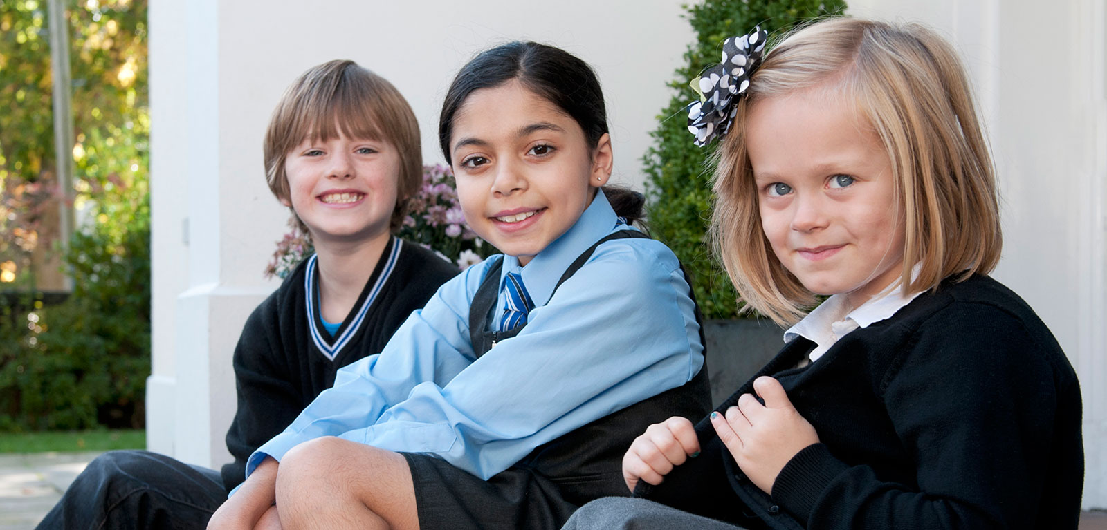 photograph of three primary school children in different school uniforms