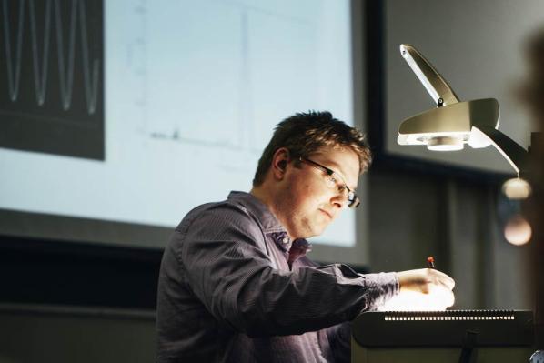 male lecturer annotating notes on a projection screen