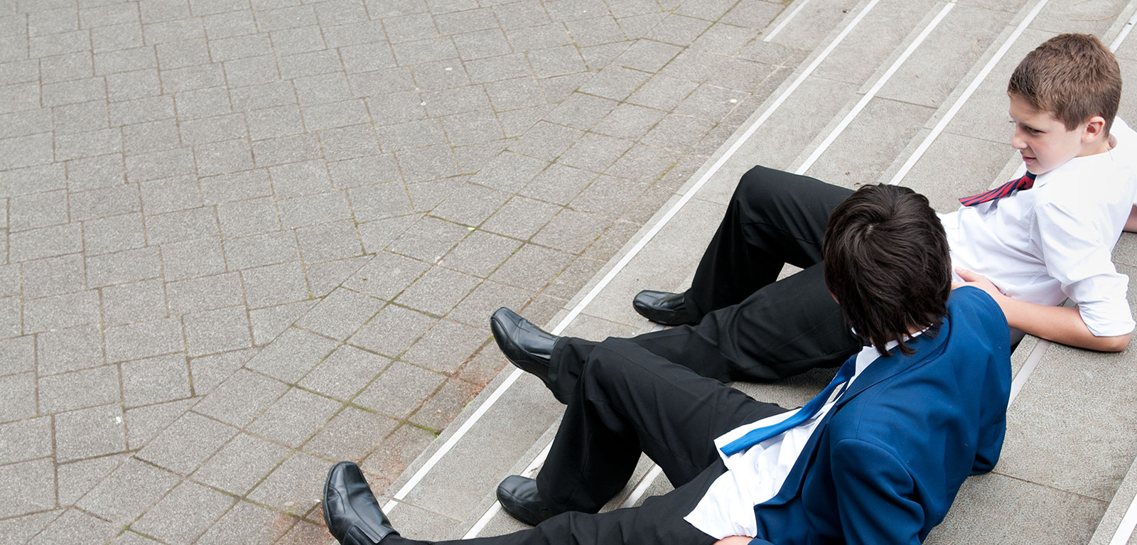 photograph taken from above looking down on two boys in different school uniforms