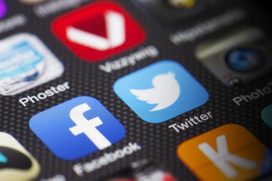 close up of a phone screen with facebook and twitter icons in view