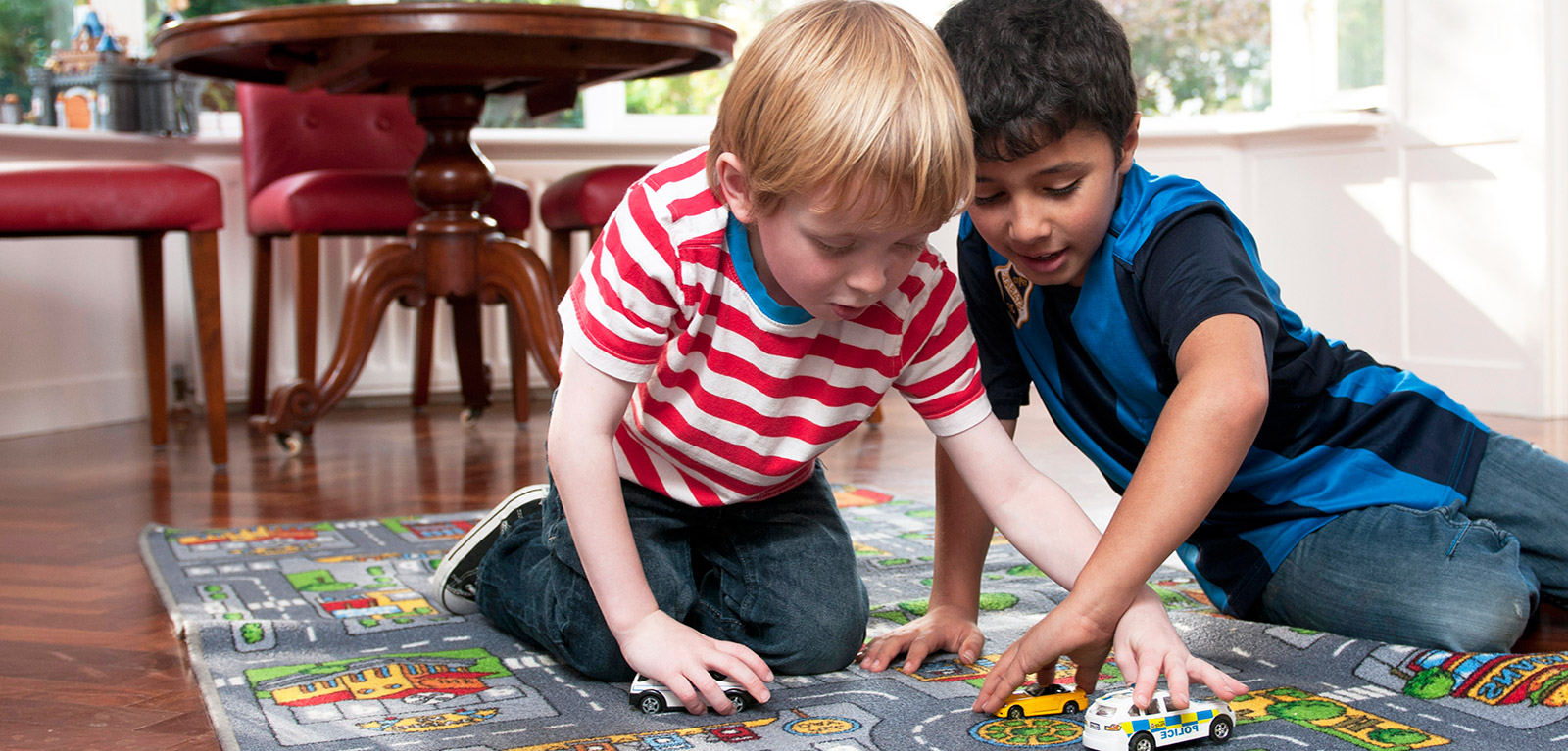 two young boys playing with cars