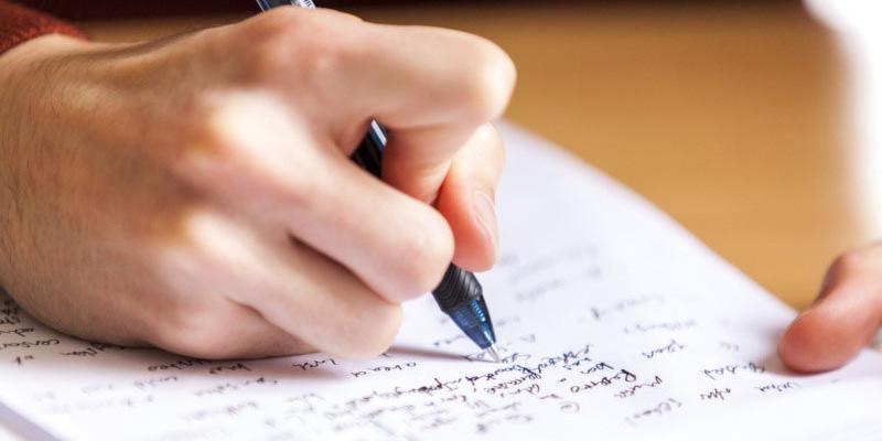 close up of a hand holding a pen and writing notes on a page