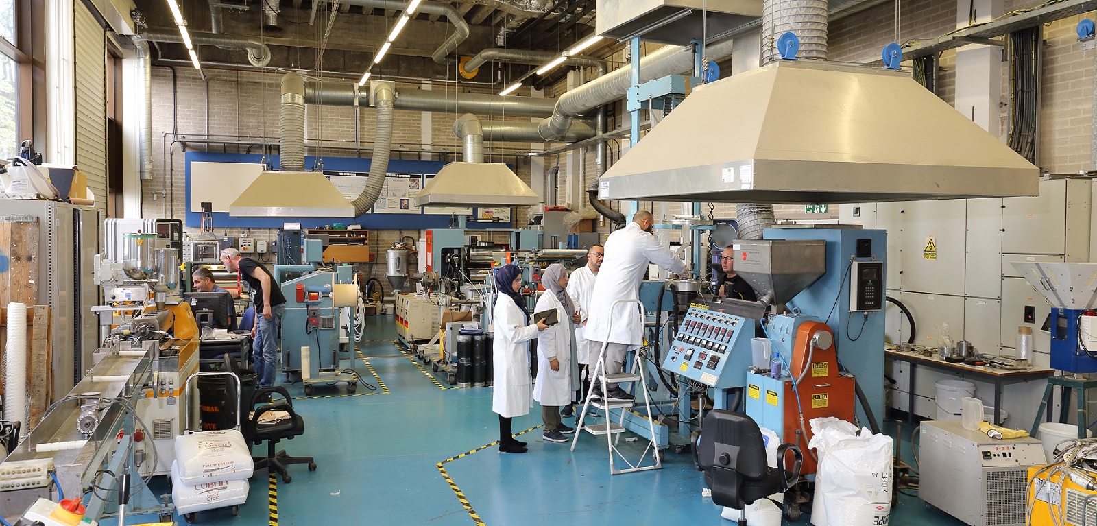 A picture of students around an extruder machine.