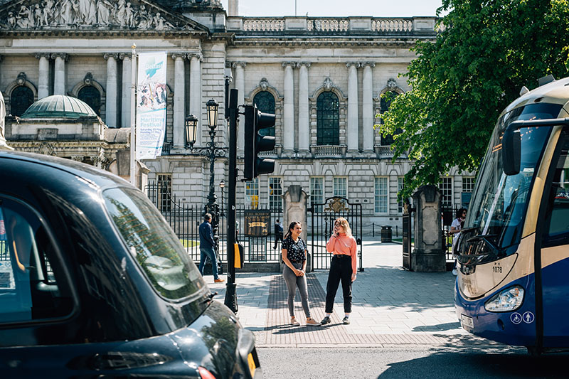 Students between a bus and a black taxi