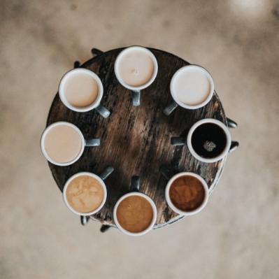 A small rounded table holds 8 coffee cups with different coffee styles