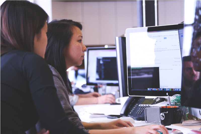 Two Asian women watching data in a computer screen