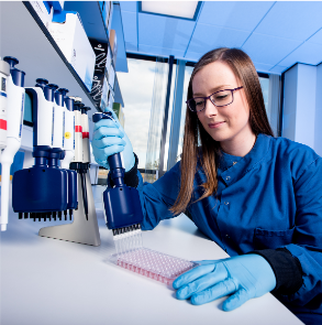 a young female researcher is wearing a bio-security outfit while injecting some fluid to tiny recipients