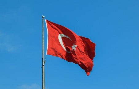 The Turkish national flag is waving with a blue sky background