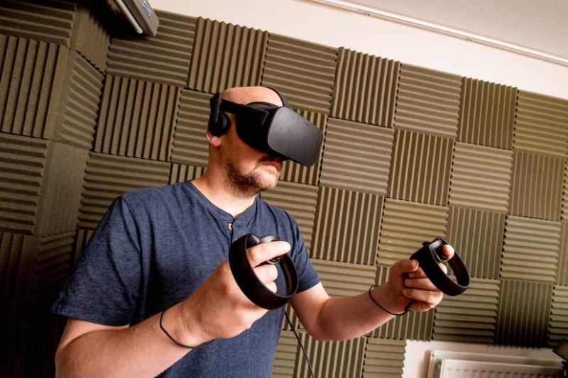 A man is wearing a VR headset and hand controls
