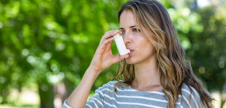 stock image of person using an asthma inhaler