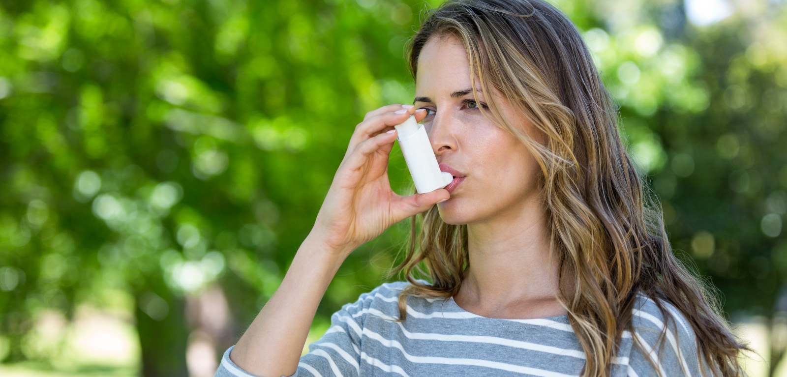 stock image of person using an asthma inhaler