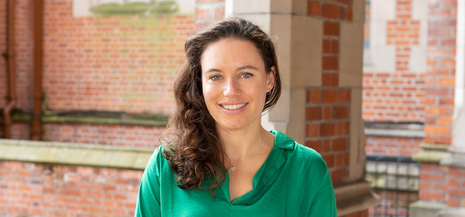 a dark haired woman wearing a green top