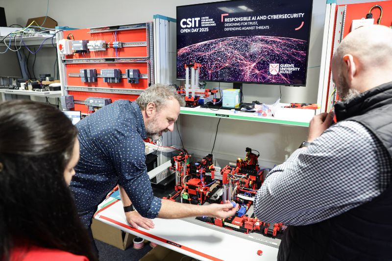 Engineer demonstrating a tech setup to industry visitors in a CSIT lab, Queen’s University Belfast.