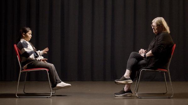 Two people sitting on chairs facing each other