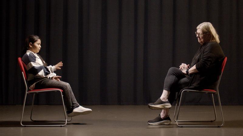 Two people sitting on chairs facing each other