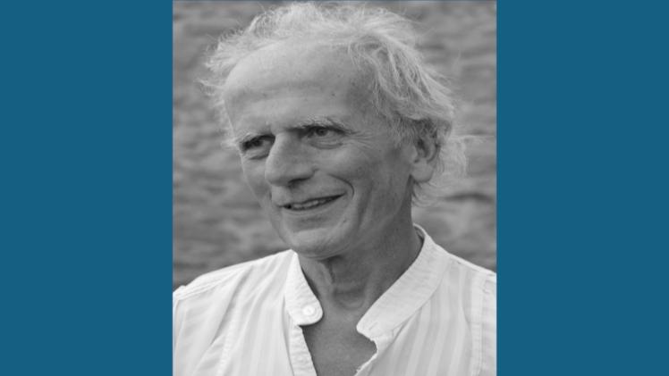 Person smiling looking to side wearing a white shirt.