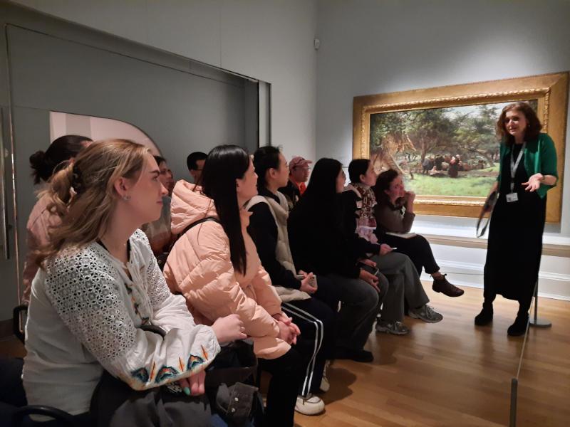 A group of people sitting in an art gallery listening to a speaker