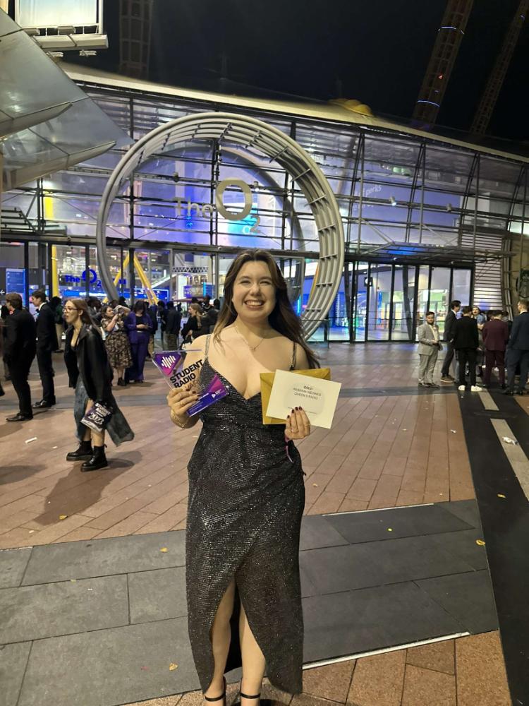 a smiling rebecca newnes standing with her award outside the o2