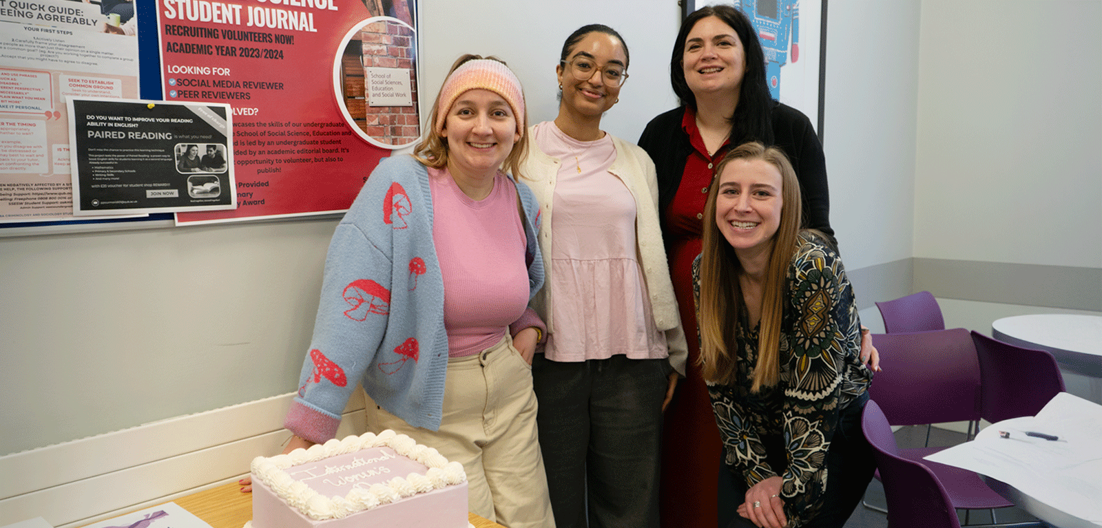 Student representatives from the SSESW Athena SWAN Student SAT pose with a IWD cake with Allely Albert and Jenny Ferguson