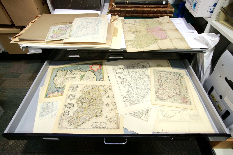 Books of ancient maps on shelves