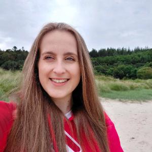 PhD Student profile photo, female student outside on a sandy beach with trees in the background
