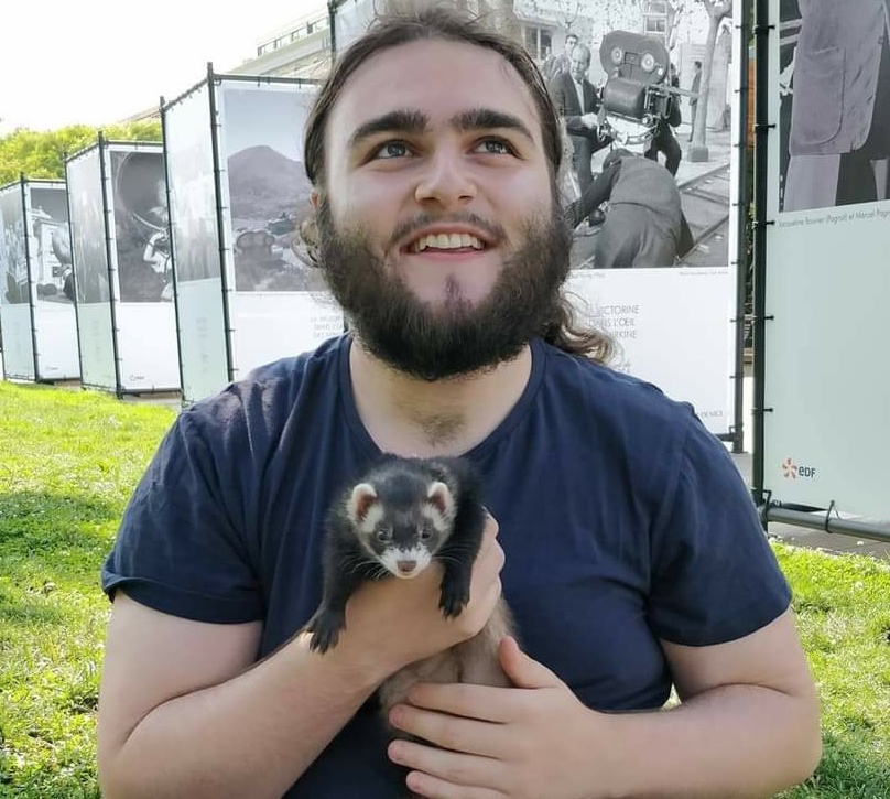 PhD student profile photo, a male student sitting outside a litte animal