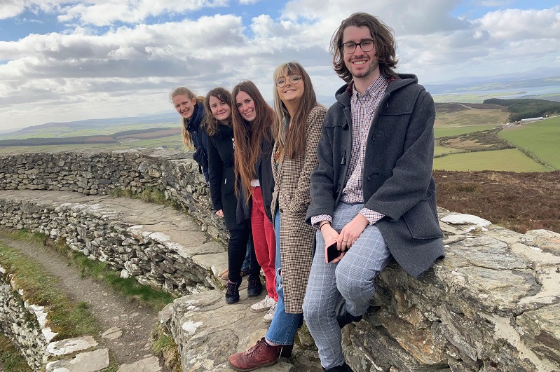 Five students sitting on the dry-stone remains of An Grianán Fort