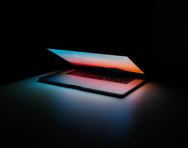 A laptop sits in the dark, slightly ajar