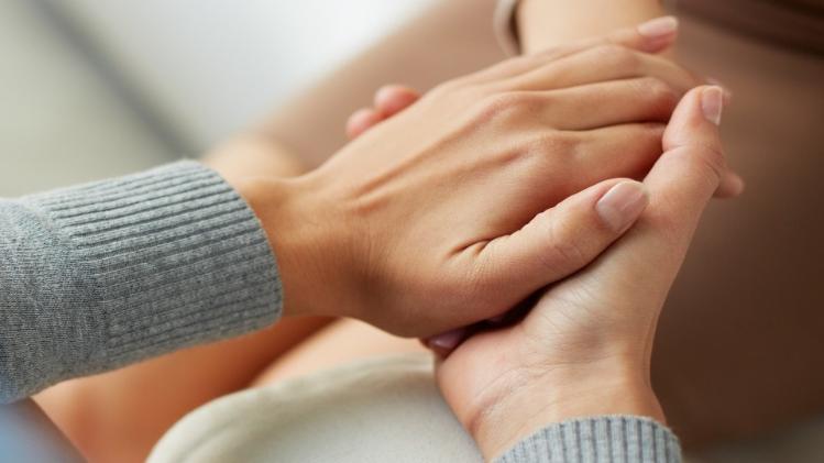 two hands in grey cardigan holding another person's hand