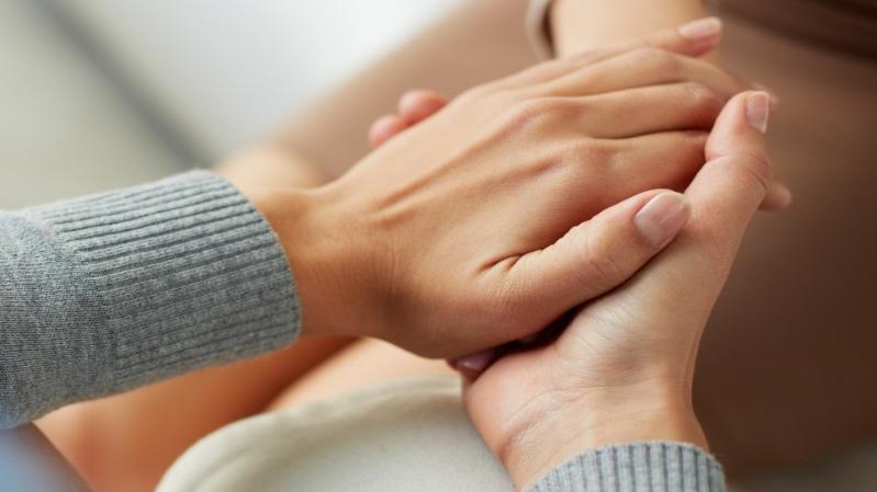 two hands in grey cardigan holding another person