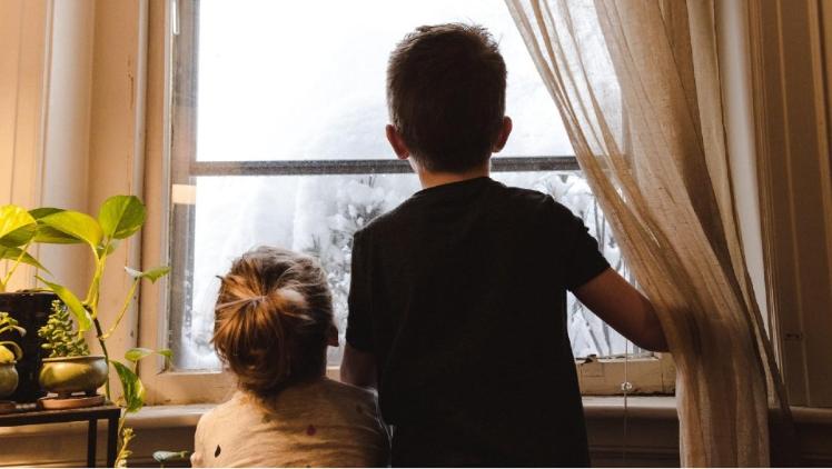 young boy and girl from behind looking out a window