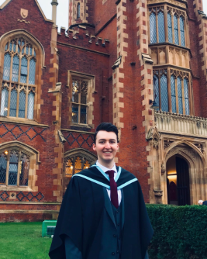 A male student outside Queen's University Belfast on graduation day wearing a graduation gown