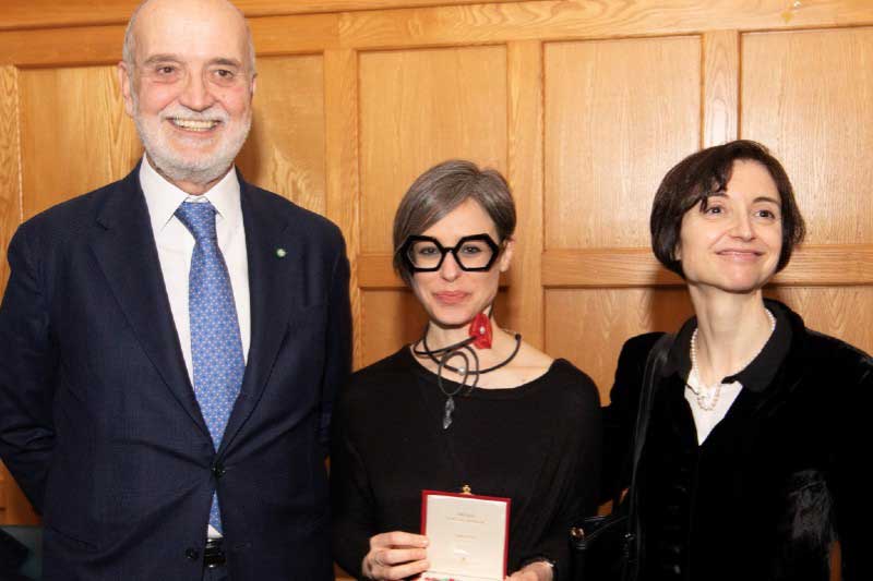 Tall man on left, small woman with short hair and glasses in middle and small woman dressed in black on right, against an oak panelled wall