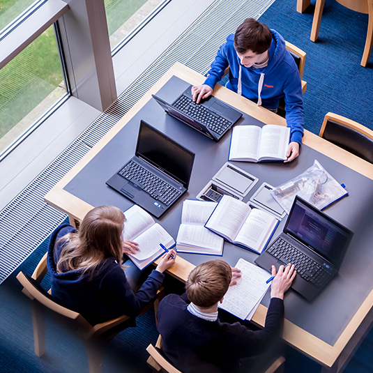 overhead view of students studying in the McClay library with laptops