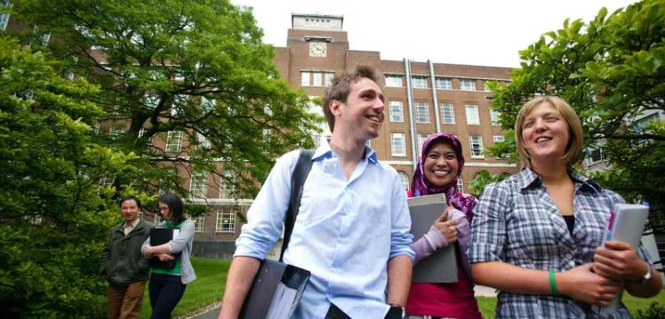 Three smiling students leaving the David Keir Building