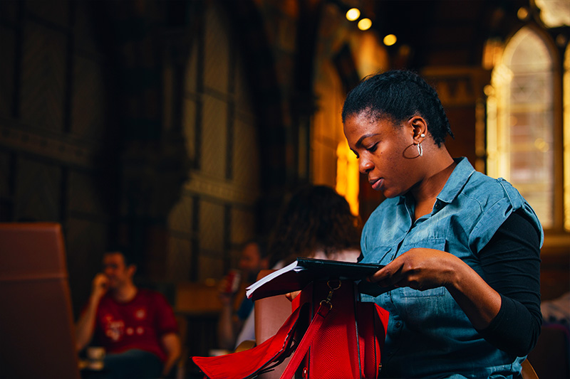 Female student in graduate school taking note out of bag