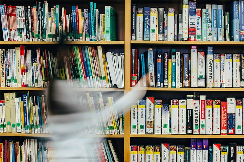 female student walking past the learning resources in the Queen's Language Centre library