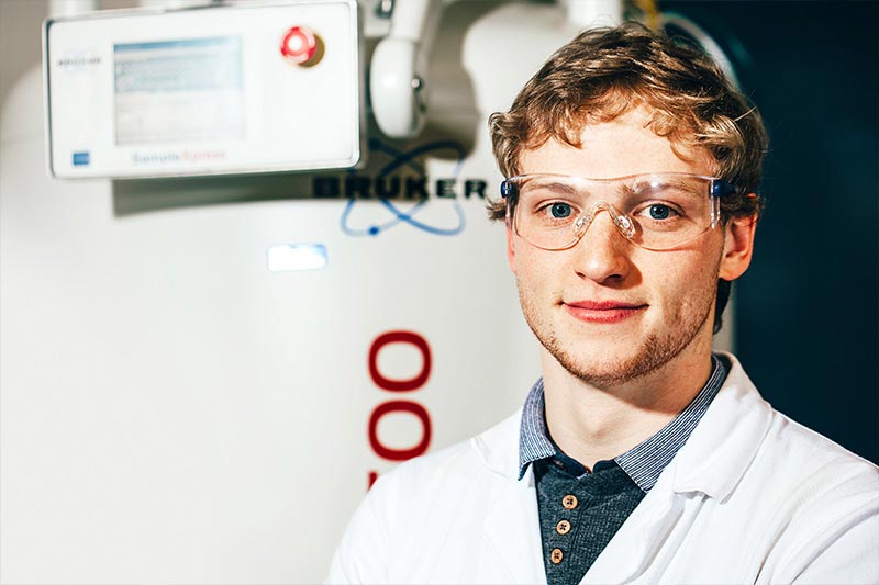 close up of ale postgraduate student in labratory wearing safety goggles and lab coat
