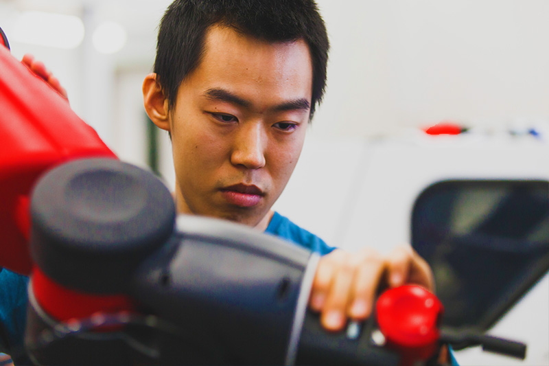 close up of a mechanical engineering student moving a robotic arm