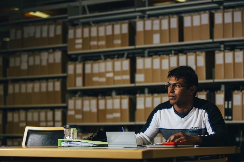 male student sitting at desk with his notes and looking off in to the distance