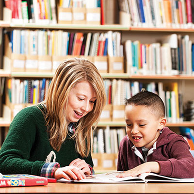 image of a teacher helping a primary school pupil with their reading