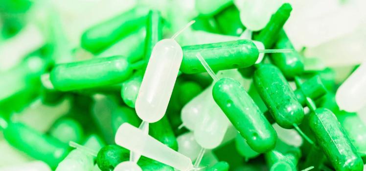 Image of green and white extruded capsules.