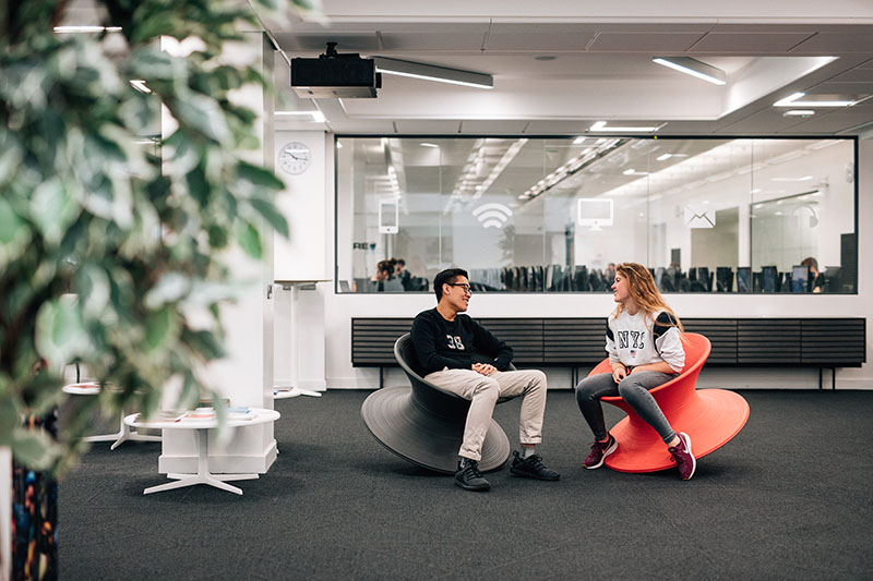 Two students seated in the spinning top chairs in the Computer Science Building