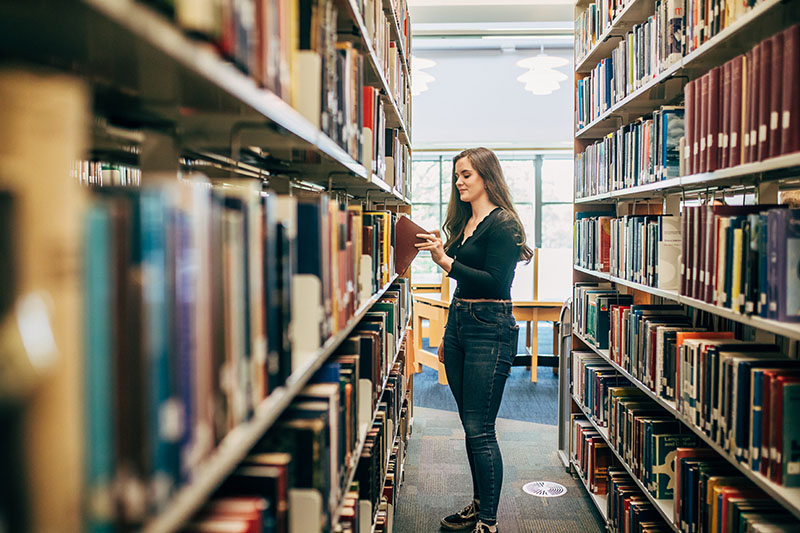 Student at bookshelves in library