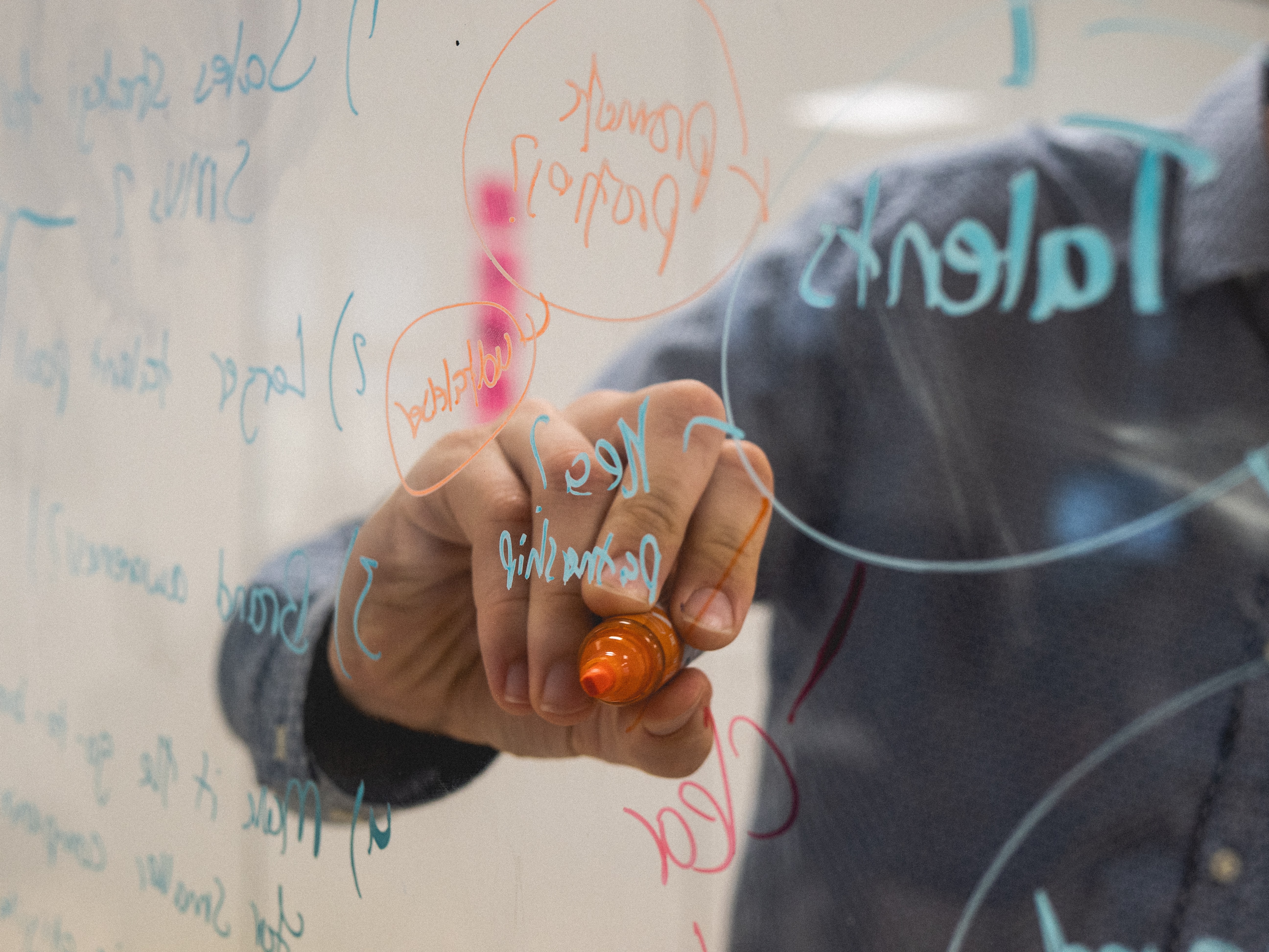 An image of a man writing on a glass panel