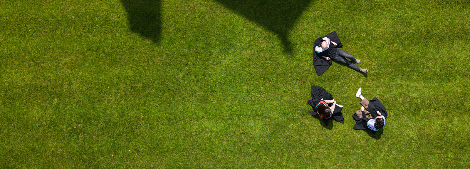 Three students in Graduation gowns in the quad